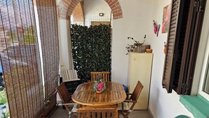 A patio with a round wooden table and chairs, a green cushioned bench, a cactus, and a decorative wall. - LaCasaDeiNonni - Lakes&Relax (Varano Borghi)