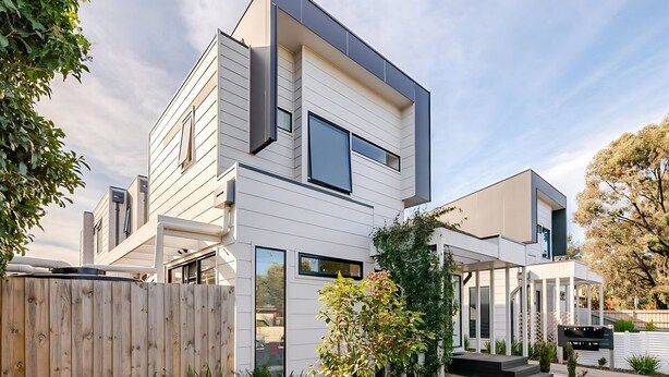 A modern two-story house with a flat roof, large windows, and a small front yard with a wooden fence and a tree. - Stunning, modern, two-story detached townhouse (Footscray)