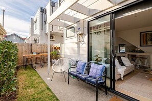 Eine moderne Terrassenanlage mit einer Couch, Sesseln und einem Tisch.