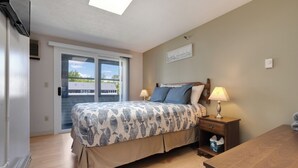 Une chambre à coucher avec un lit, des lampes de chevet, une table de chevet et une vue sur l’extérieur, accessible par une porte coulissante.