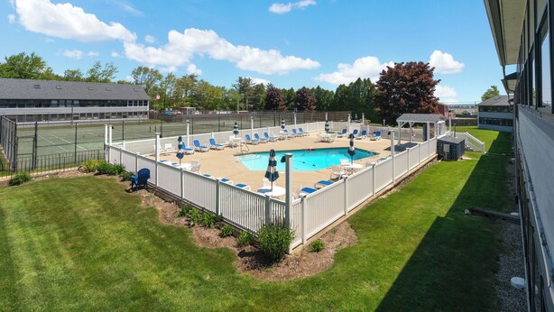 Une cour arrière clôturée avec une piscine, des chaises longues et un petit pavillon.