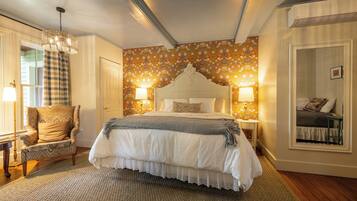A bedroom with a large bed, two bedside tables with lamps, a chair, and a mirror.