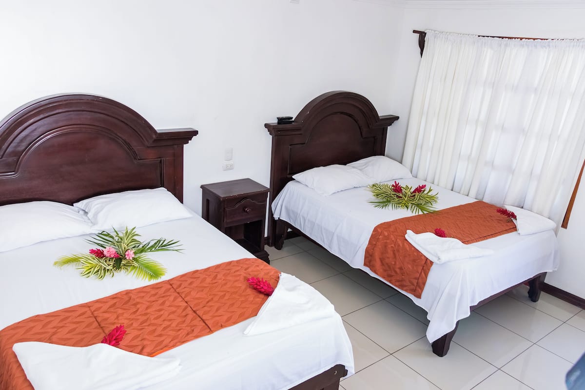 Two double beds with wooden headboards, white linens, and orange throw blankets.