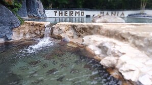 Una fuente de agua con cascada, rodeada de rocas y follaje.