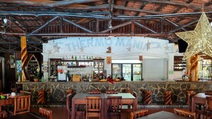 Un restaurante con un interior rústico, que presenta vigas de madera a la vista y una pared de piedra.
