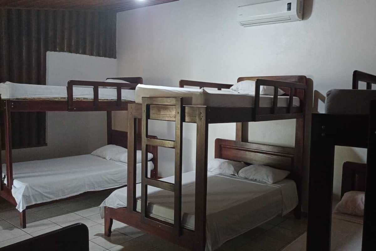 A dormitory room with bunk beds, a window, and an air conditioning unit.
