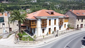 Un edificio de dos pisos con techo de tejas rojas, muros de piedra y varias ventanas.