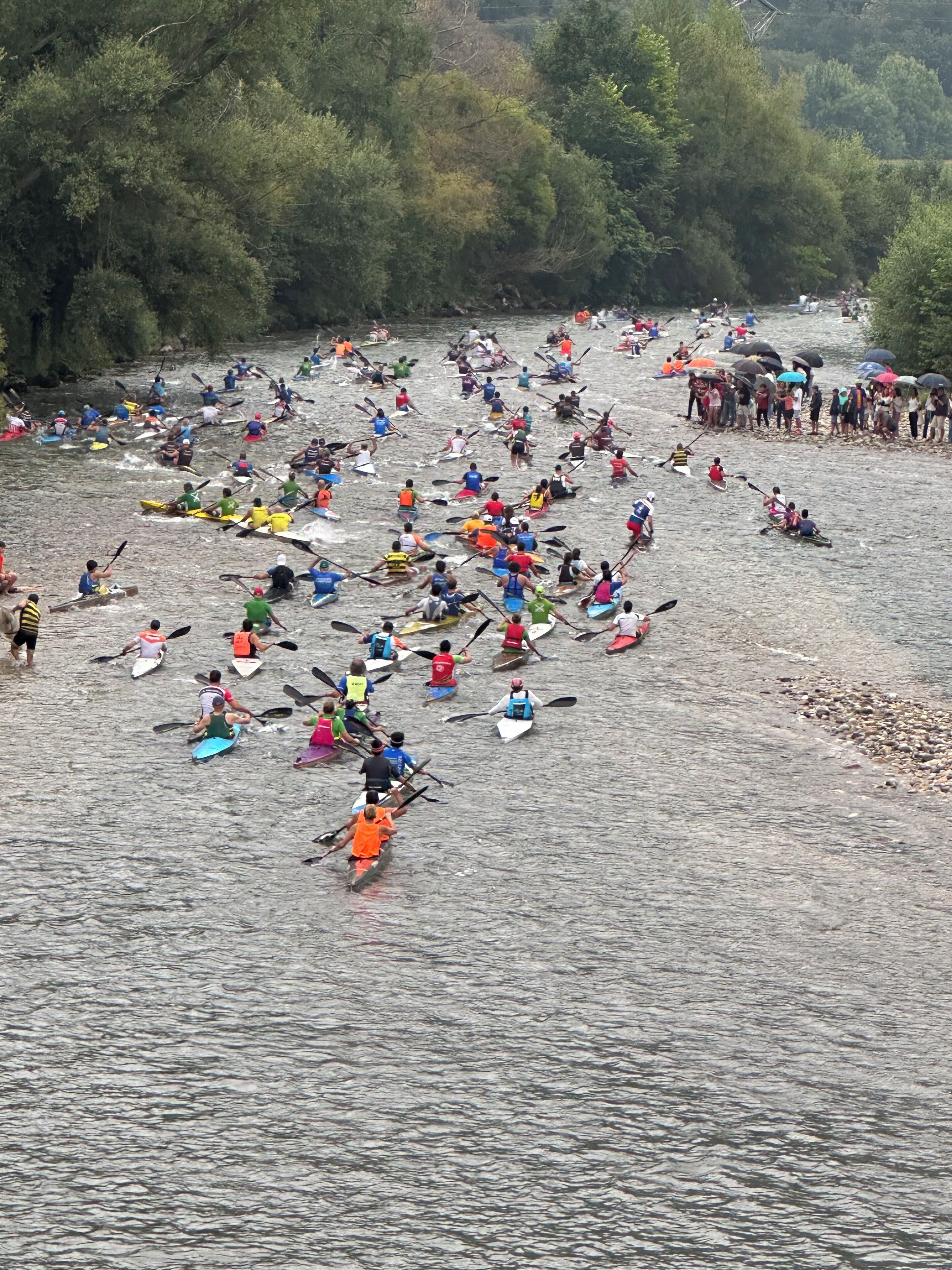 Un río con varias personas remando en canoas y kayaks.