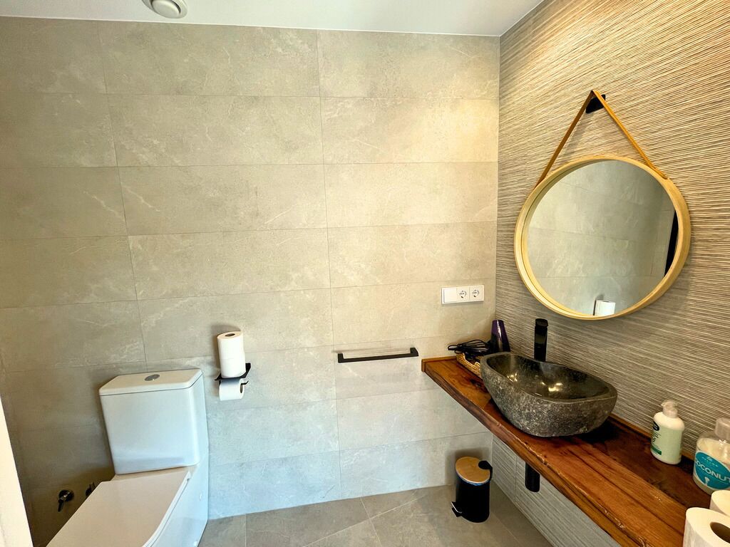 Une salle de bain moderne avec des toilettes, un lavabo et un miroir.