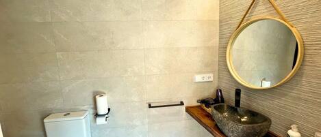 A modern bathroom with a toilet, sink, and mirror.