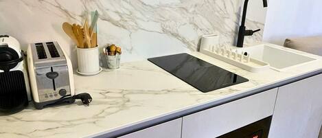 A modern kitchen with a marble backsplash, a built-in oven, a sink, and a toaster.