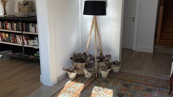 Una habitación con piso estampado, una lámpara de pie, una estantería y una puerta que da a otra habitación.