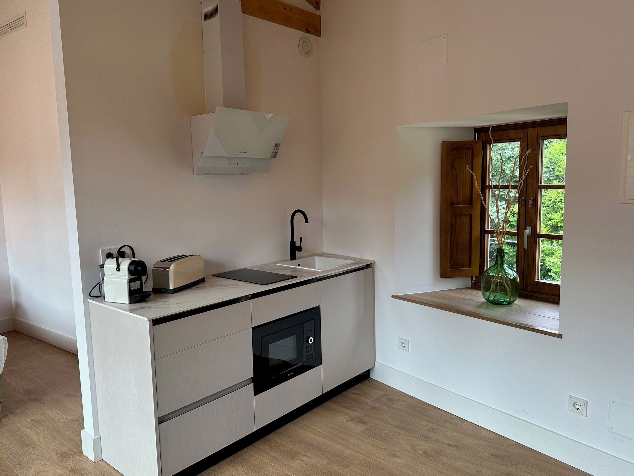 A modern kitchen with a built-in microwave, a toaster, and a coffee maker on the countertop.