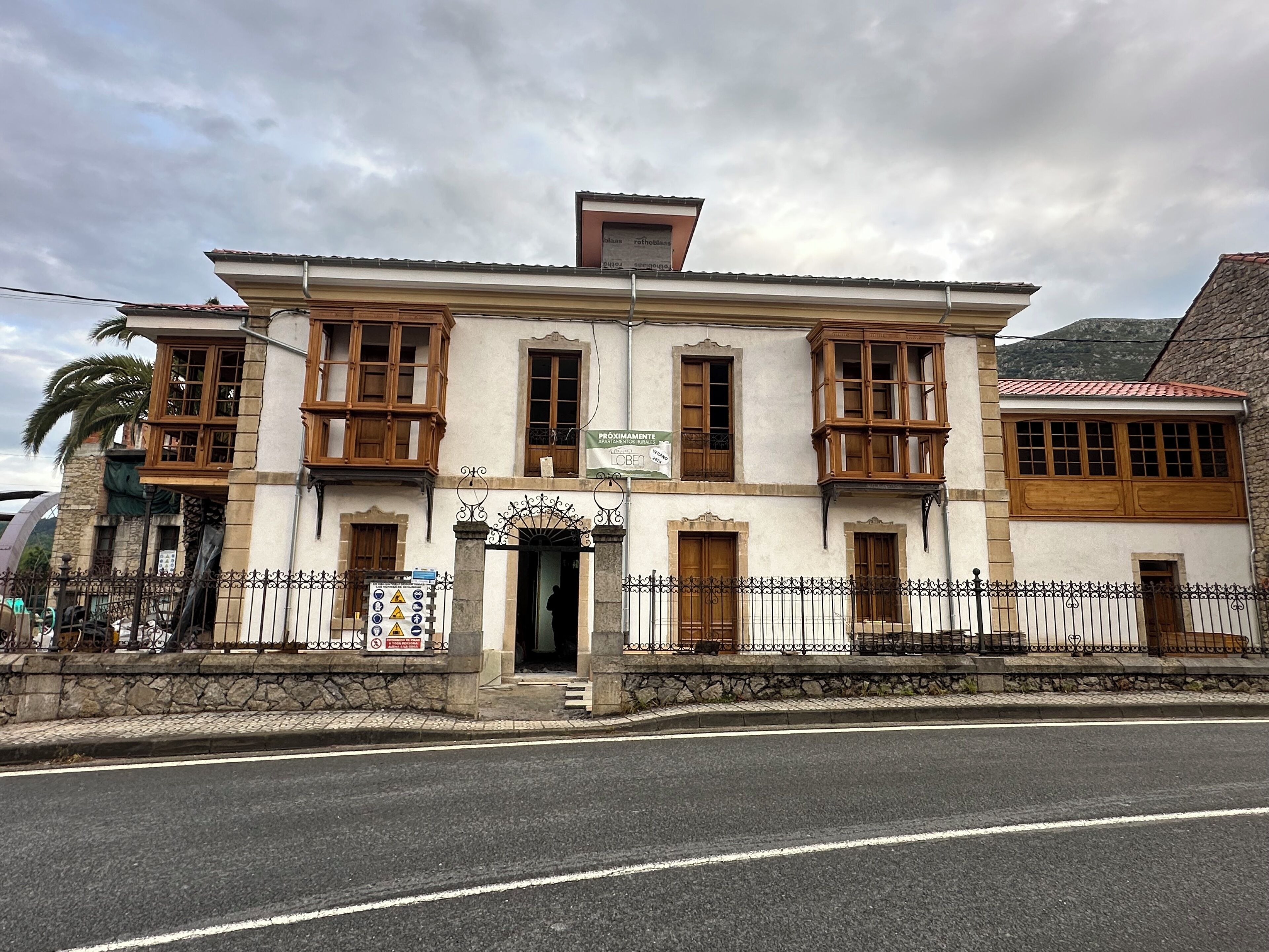 A two-story building with a traditional architectural style, featuring wooden balconies and a stone facade.