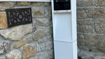 Caja de medidores de servicios instalada en una pared de piedra, junto a un cuadro eléctrico blanco.