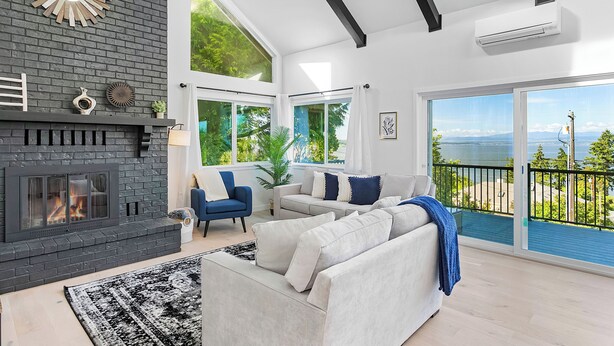 A modern living room with a fireplace, large windows, and a balcony with a view. - Peaceful Island Getaway Port Susan views (Camano Island)