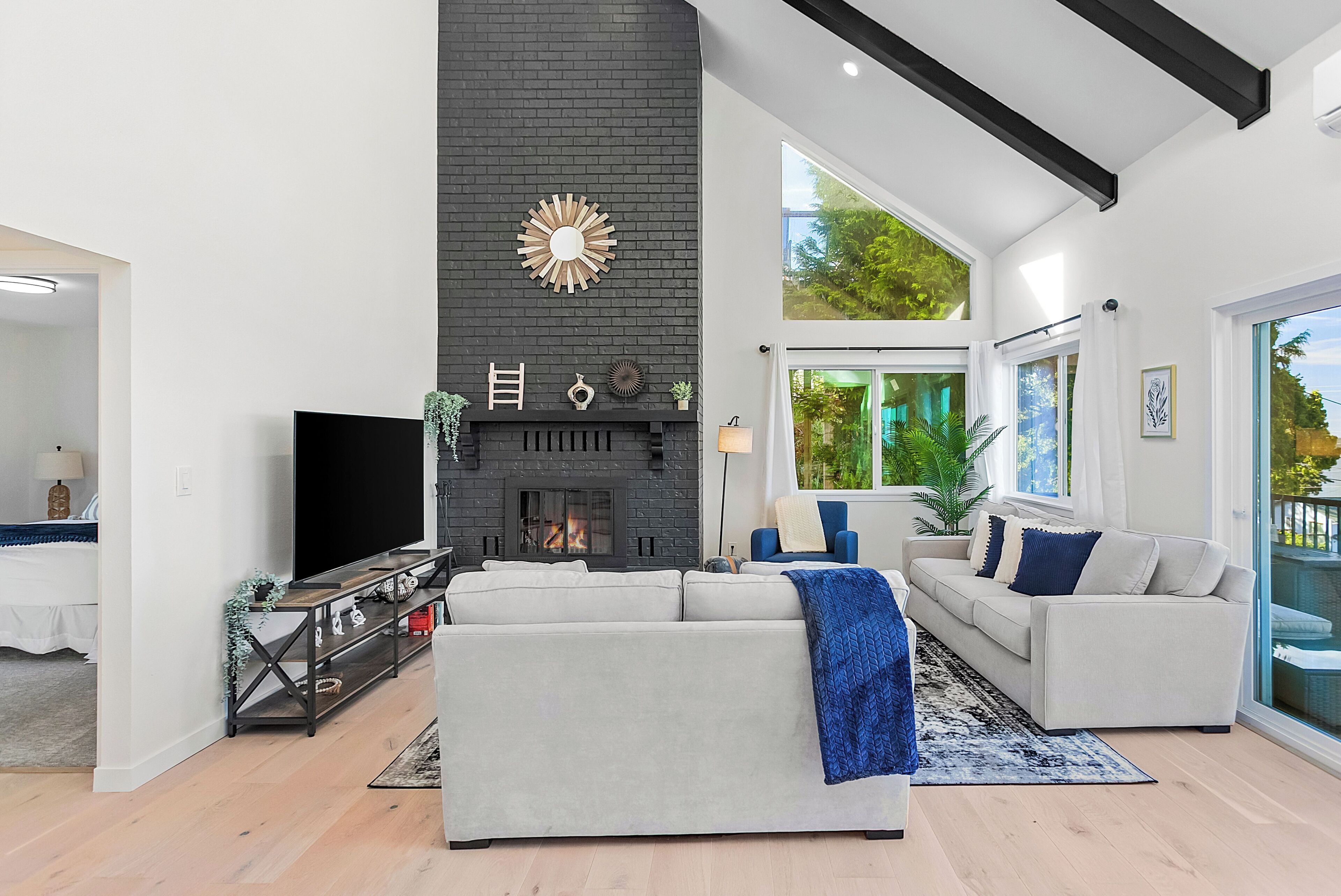 A modern living room with a fireplace, a large TV, and a sofa.