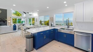 A modern kitchen with blue cabinets, a white countertop, and a dishwasher. - Peaceful Island Getaway Port Susan views (Camano Island)