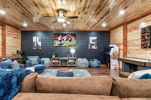 A cozy living room with a fireplace, comfortable seating, and a large TV screen.