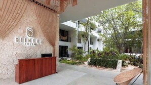 Zona de recepción con pared de piedra, mostrador de madera e iluminación colgante de fibra.
