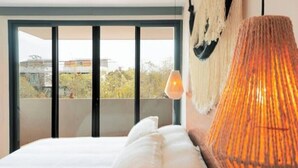 Un dormitorio con un ventanal grande, una cama y una lámpara colgante.