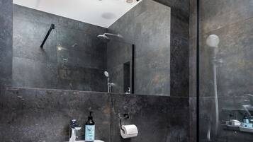 A modern bathroom with a large mirror, a white sink, and a glass-enclosed shower.