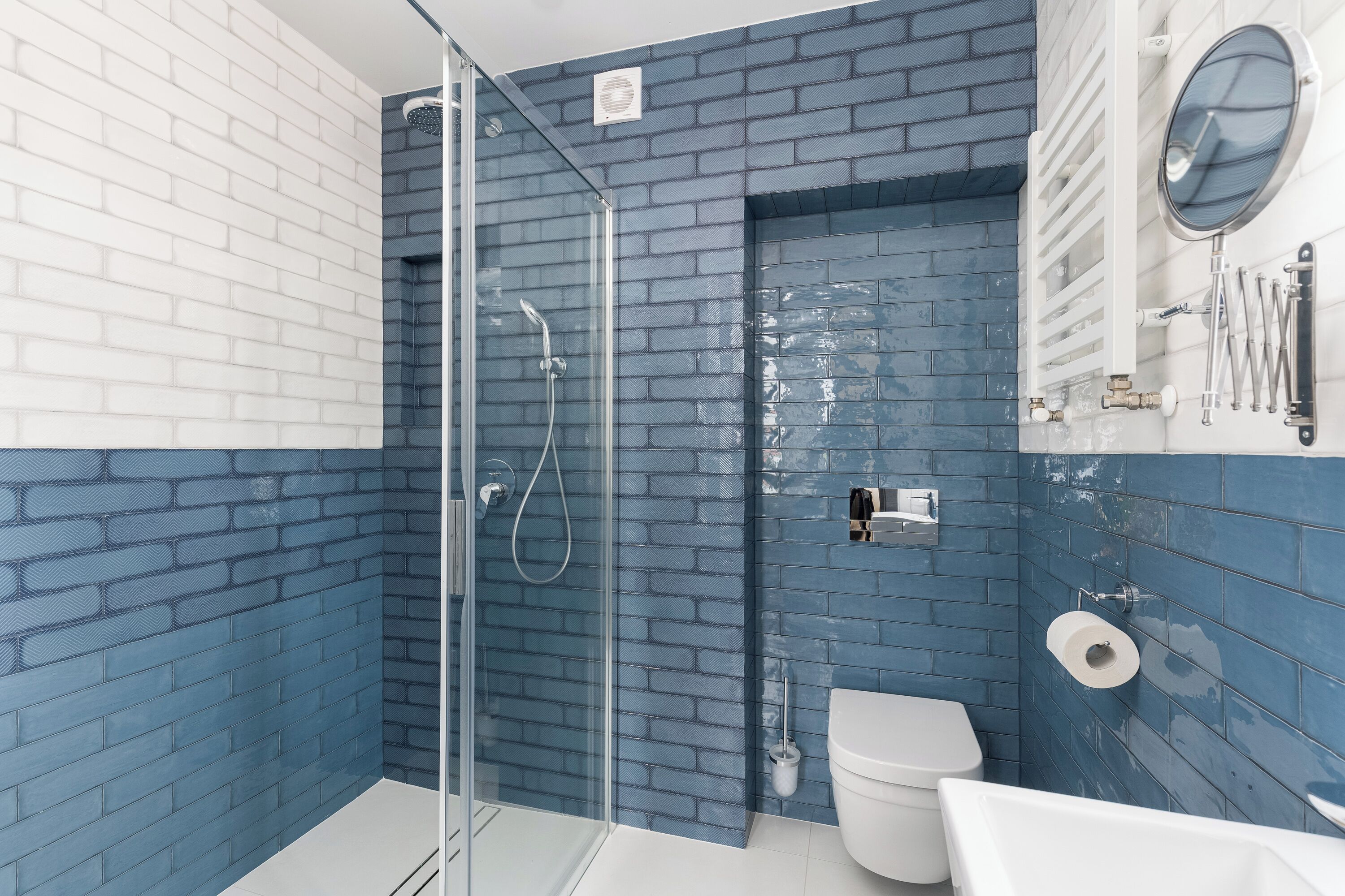 A bathroom with a glass shower enclosure, a toilet, and a sink.