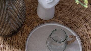 Uma mesa de fibra natural com um jarro de cerâmica e um vaso com flores.