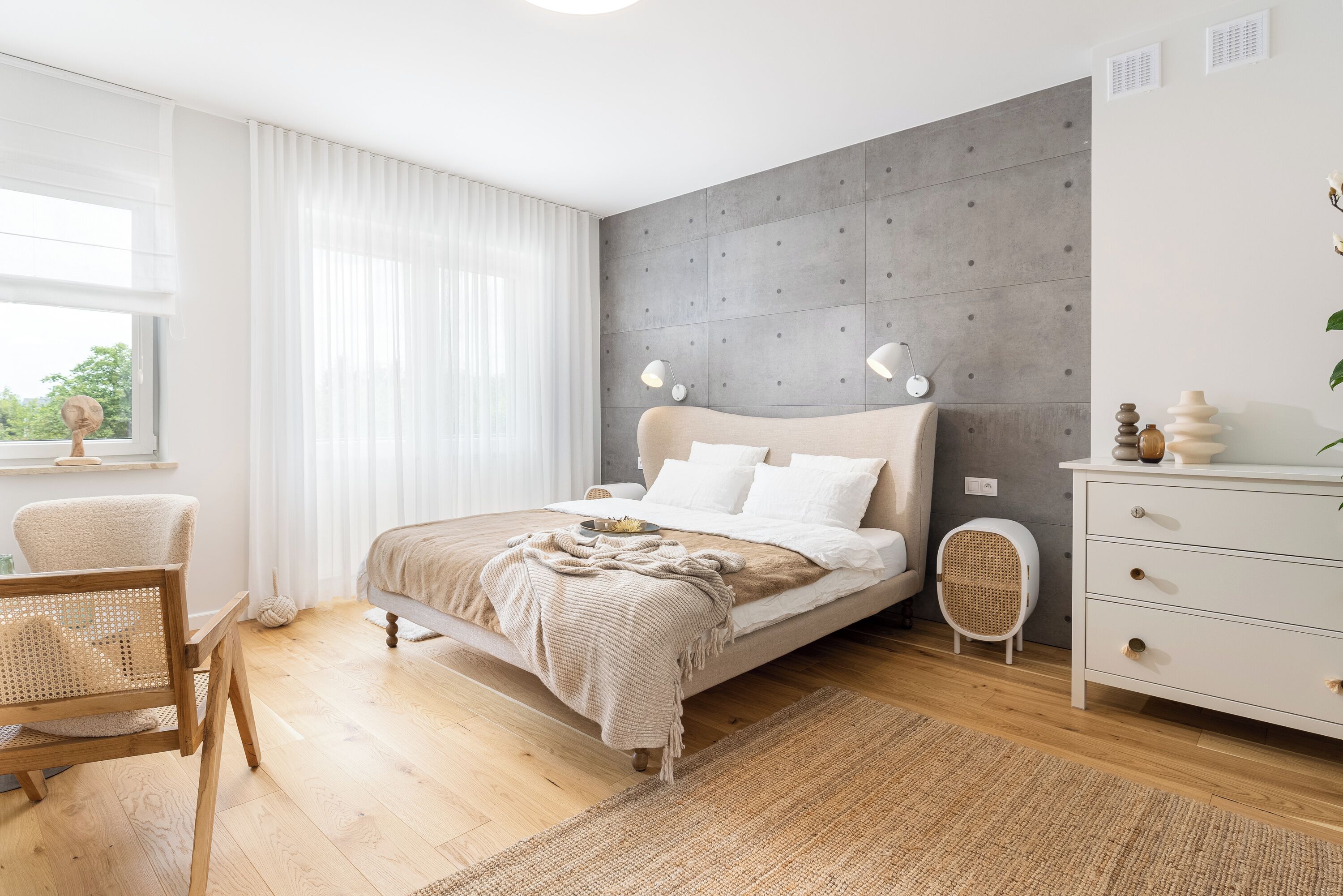 Un dormitorio moderno con una cama, mesitas de noche, una silla y una ventana con cortinas.