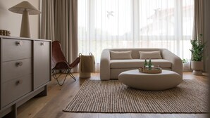 Una sala de estar moderna con un sofá, una mesa de centro con bebidas, una lámpara y una silla.