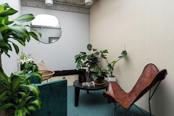 A small, cozy room with a round table, a leather chair, and several potted plants.