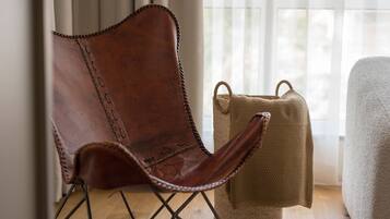 A brown leather chair with metal legs, a woven basket, and a white upholstered armchair.
