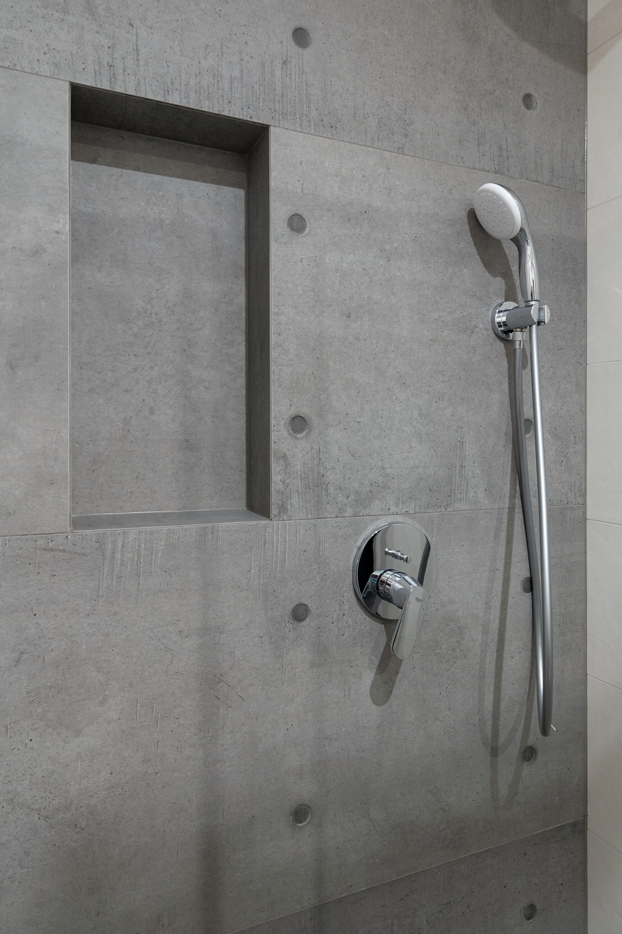 Ducha con cabezal de ducha de mano y llave de control en la pared.