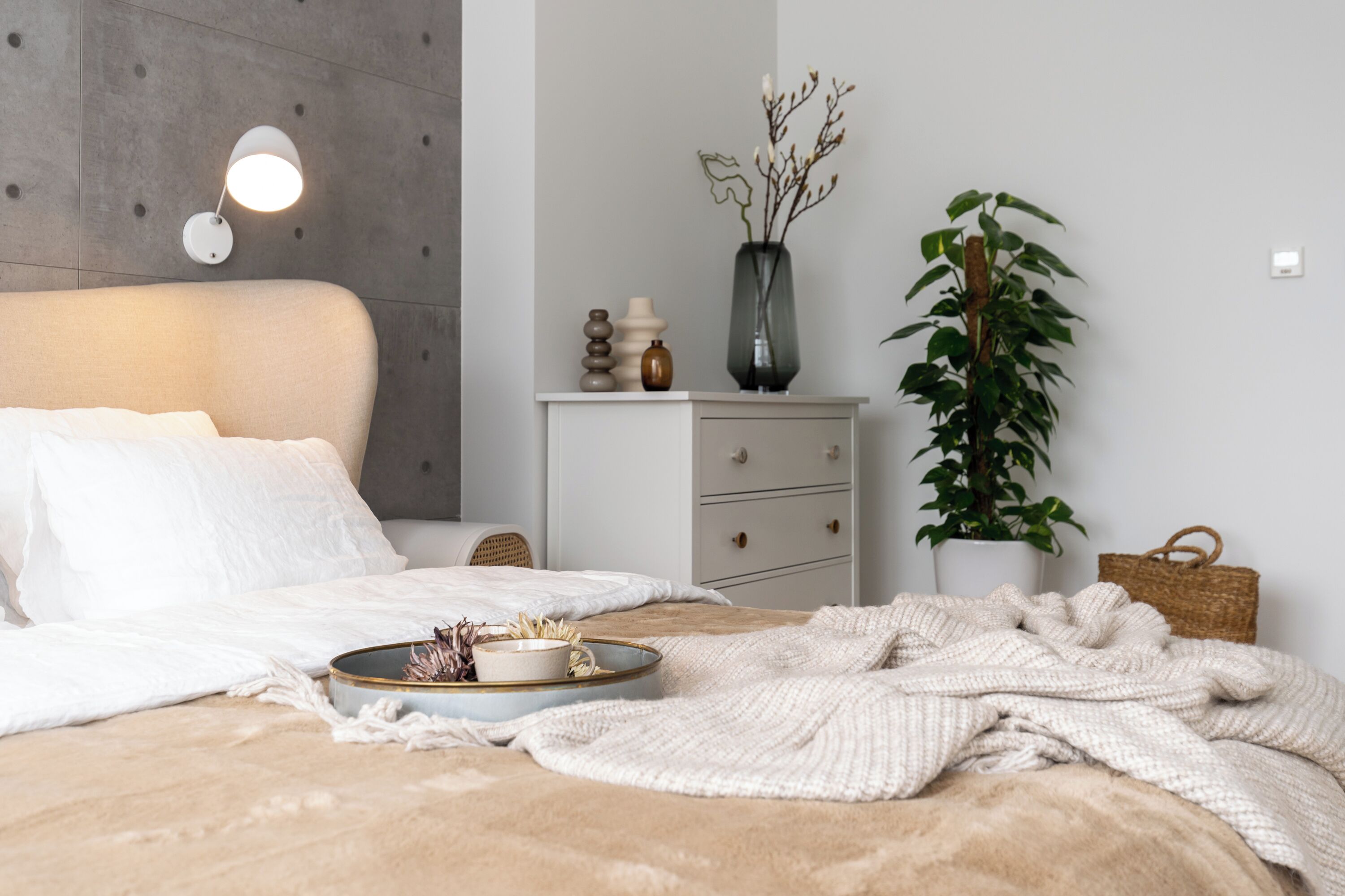 Une chambre à coucher bien rangée, avec un lit, une table de chevet, une lampe et une plante en pot.