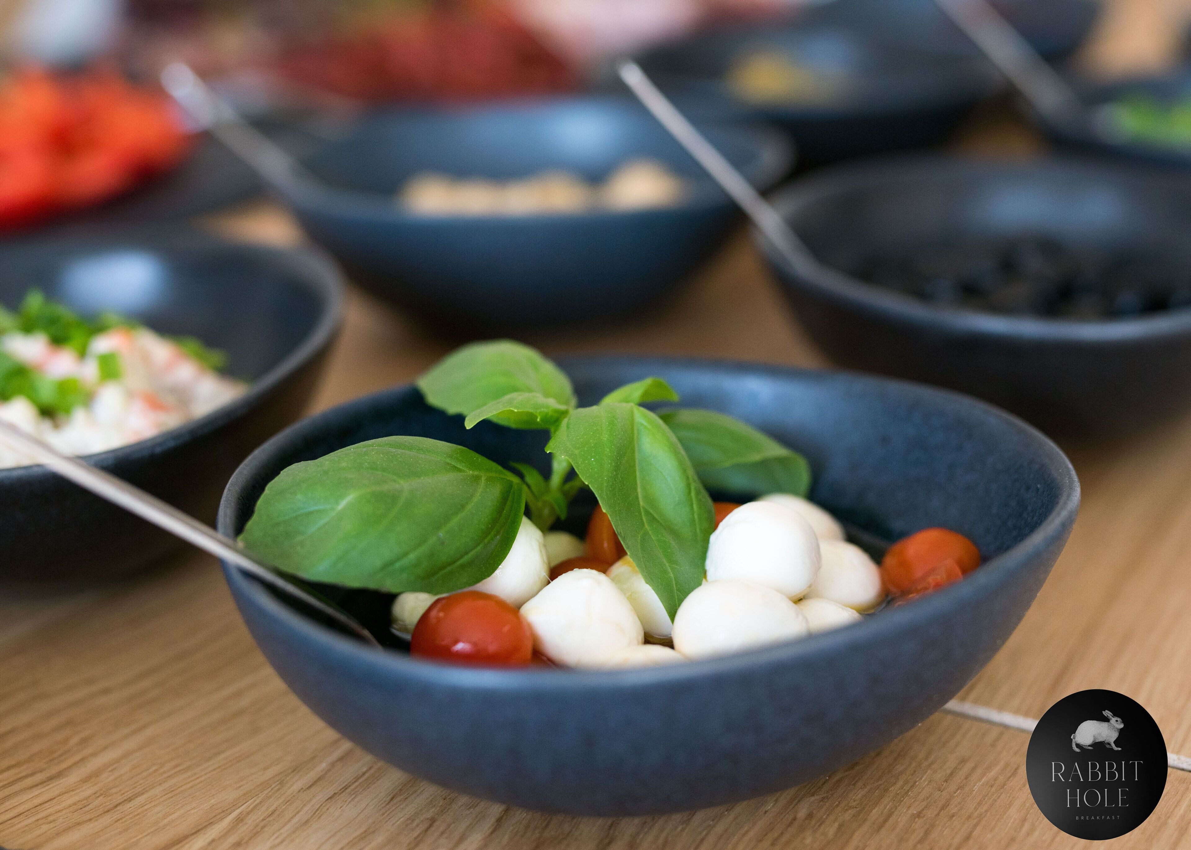Un plato de comida con hojas de albahaca y tomates cherry.