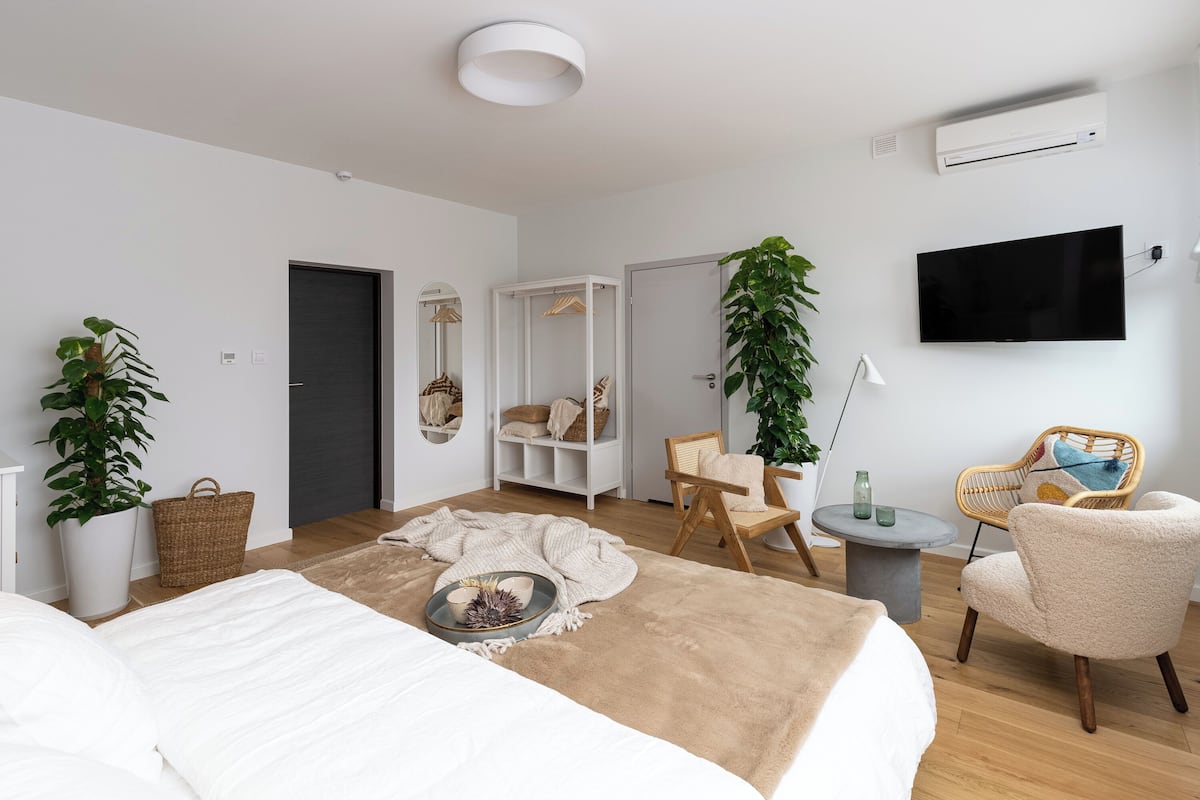 A modern bedroom with a large bed, a TV, a chair, and a wardrobe.