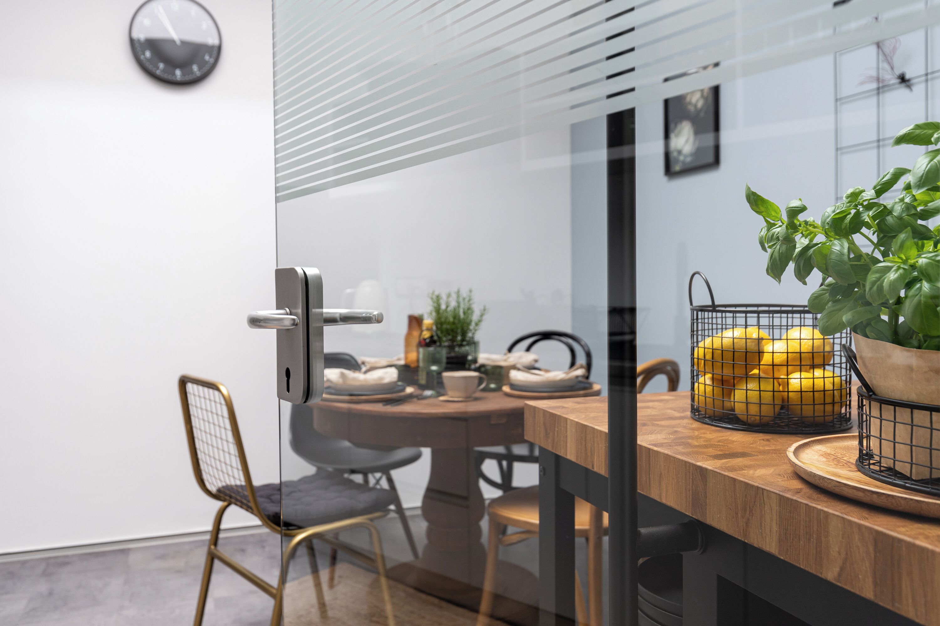 A modern dining area with a wooden table, chairs, and a glass partition.