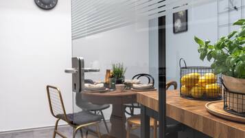 A modern dining area with a wooden table, chairs, and a glass partition.