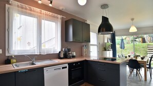 Une cuisine moderne équipée d’un lave-vaisselle, d’un four et d’un coin repas avec une table et des chaises.