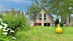 Une maison d’habitation avec une pelouse bien entretenue, un ornement de jardin jaune et une porte rouge.