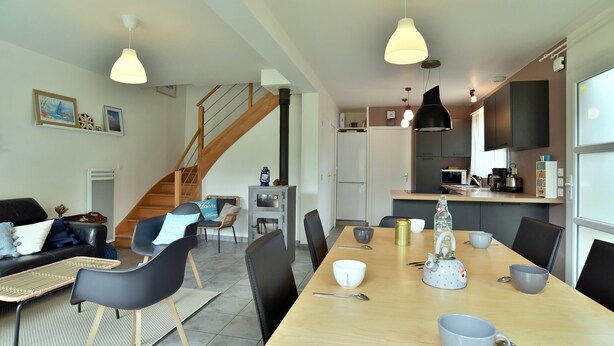 Une cuisine moderne avec un coin repas, un escalier et un salon comprenant un canapé et une table basse.