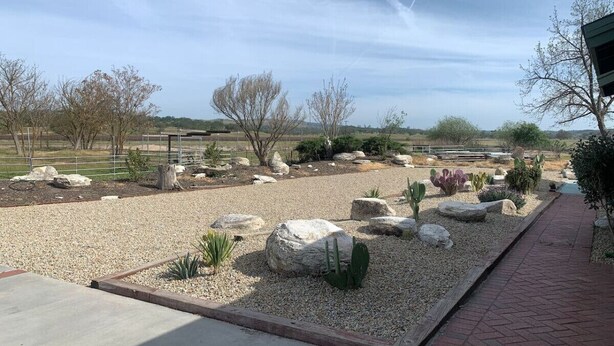 Un jardin aménagé avec des rochers, des cactus et un sentier dallé.