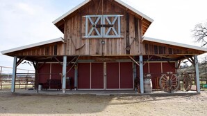 Une grange en bois avec une grande porte de grange, une entrée couverte et une grande roue.