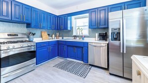 Une cuisine moderne avec des armoires bleues, des appareils en acier inoxydable et un tapis à motifs.