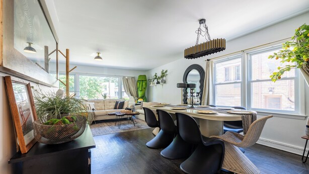 Un espace repas moderne avec une table ronde, des chaises noires et un luminaire suspendu.
