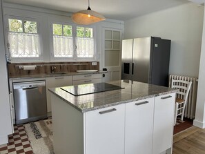 Een koelkast, een oven, een vaatwasser, kookgerei, borden en bestek