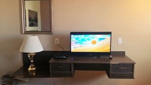 A desk with a television, a lamp, and a remote control. - Lamplighter Viking Motel (Viking)