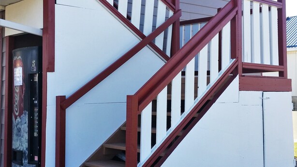 A staircase with red railings leading to a building entrance. - Lamplighter Viking Motel (Viking)