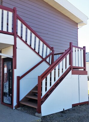 A staircase with red railings leading to a building entrance. - Lamplighter Viking Motel (Viking)