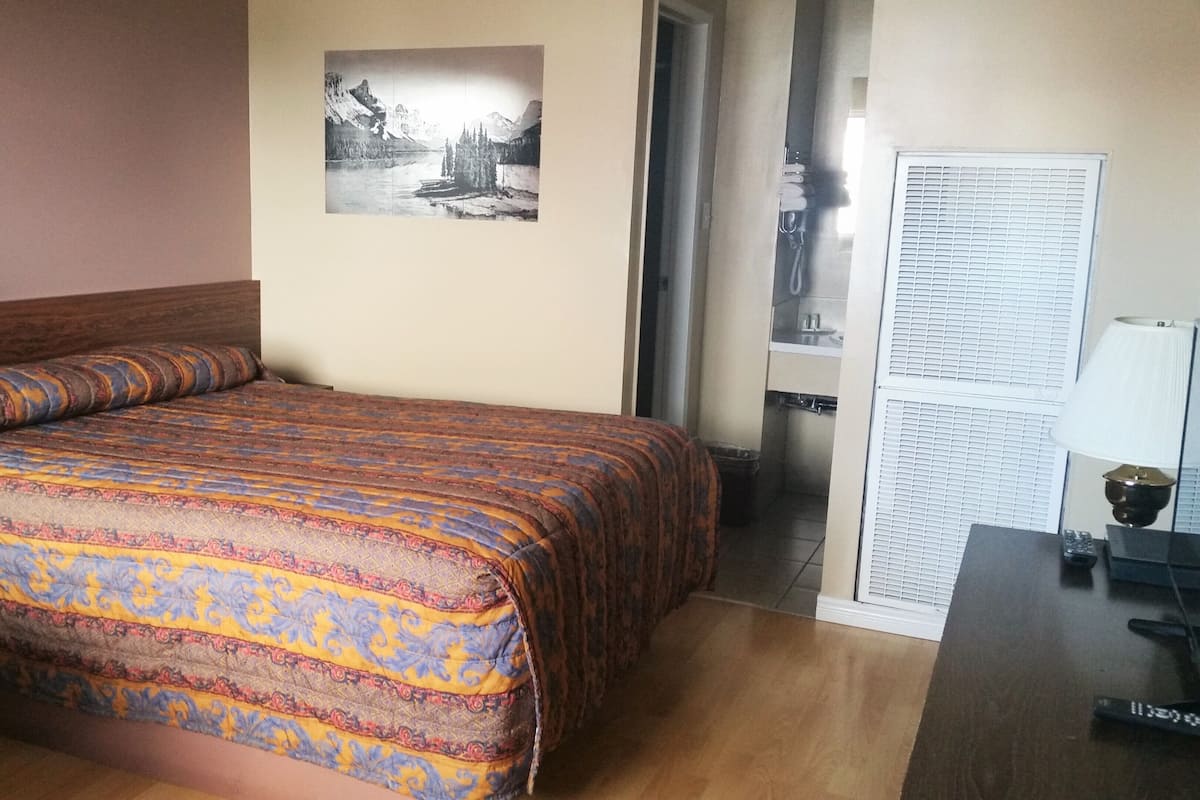 Una habitación de hotel con cama, baño y ventana.